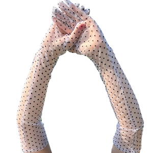 Detail of white mesh long gloves with black polka dots on a model against white background