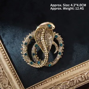 Detail of vintage cobra brooch with gold metal scales and green rhinestone eyes