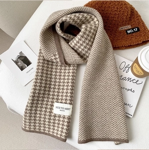 Close-up of knit houndstooth scarf texture with warm brown beanie and autumn accessories