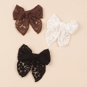 Close-up of hollow lace bow hair clips in brown, white and black for girls