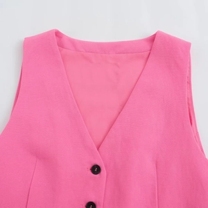 Détail du gilet rose montrant le col en V, la texture du tissu et les boutons noirs