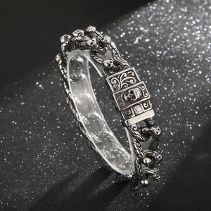 Detail of punk skull bracelet with intricately carved clasp on a black glitter background