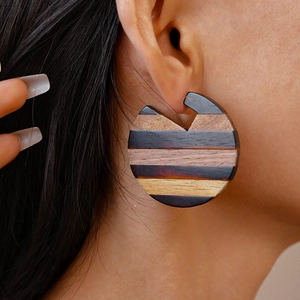 Close-up of geometric round wooden earrings featuring vintage striped wood grain patterns