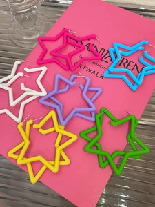 Close-up of interlocking colorful star earrings in pink, blue, white, purple, yellow, and green