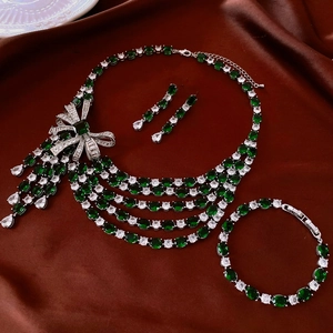 Exquisite silver necklace set with green crystals and bow tassels on dark red silk