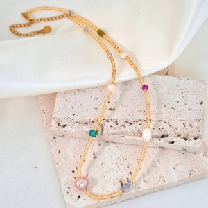 Handmade freshwater pearl and colorful natural stone beaded necklace on white silk fabric
