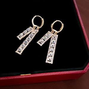 Close-up of gold geometric drop earrings with pave-set zircon crystals on black velvet