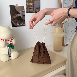 Brown corduroy baby bear drawstring storage pouch being held by hand in a cozy setting