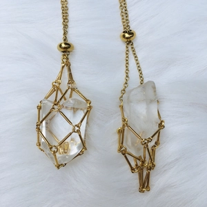 Detailed close-up of handmade gold metal cage pendants with clear natural crystals