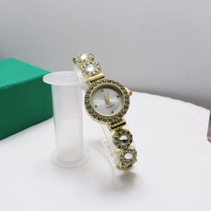 Detail of a gold quartz watch with rhinestones and pearl-like inlay on a bracelet band