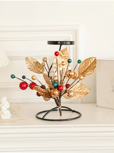 Close-up of golden metal candle holder with red berries and glitter leaf ornaments