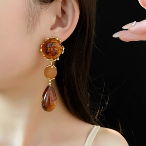 Detail of vintage amber resin floral drop earrings with gold metal accents on model