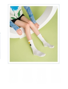 Close-up of white crew socks with yellow smiley face patch on soft cotton fabric