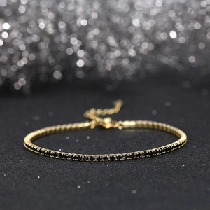 Macro shot of 2mm gold-plated silver tennis bracelet featuring black round-cut stones