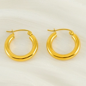 Flat lay of vintage 18K gold plated stainless steel round hoop earrings on white fabric