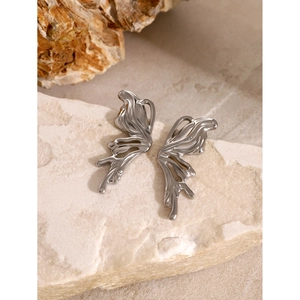 Macro shot of silver liquid metal butterfly stud earrings on a textured stone background