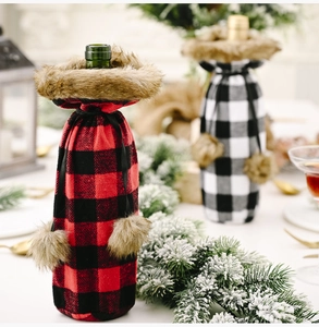 Detail of red and black plaid wine bottle covers with faux fur trim on a holiday table