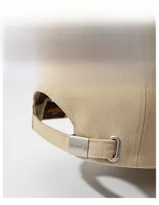 Close-up of adjustable metal buckle on khaki cotton baseball cap with PineCrest logo