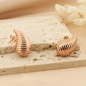 Chic hollow spiral teardrop earrings in rose gold finish on a decorative stone tray