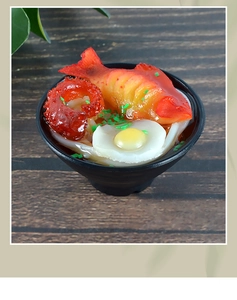 Macro shot of realistic Japanese ramen bowl model with octopus, egg, and seaweed details