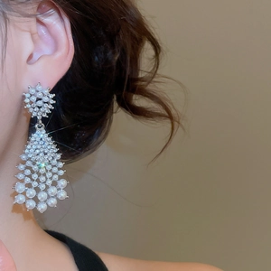 Close-up of model wearing silver pearl drop earrings with sparkling rhinestones