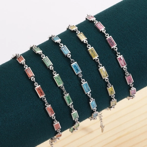 Détail de cinq bracelets en zircon coloré rectangulaire sur présentoir en velours vert