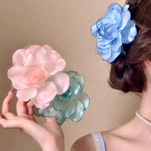 Detailed view of large fabric flower hair clips in soft pink, blue, and green organza