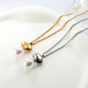 Elegant gold and silver stainless steel necklaces with large pearls on white ceramic