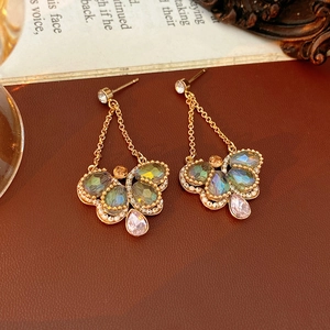Macro detail of vintage butterfly drop earrings with colorful gems and white pearls
