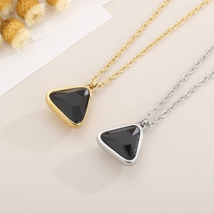 Detailed flat lay of gold and silver necklaces with black triangle crystal pendants