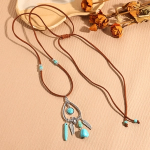 Detail of bohemian necklace with turquoise stones and vintage silver feather pendants