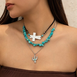 Detail of layered bohemian necklaces featuring a cross pendant and turquoise stone beads