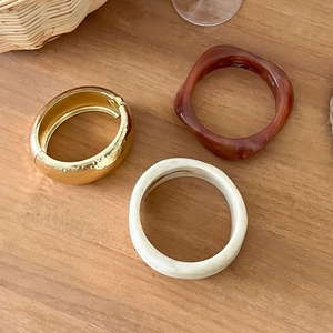 Bracelets larges irréguliers en résine et métal doré martelé sur fond en bois