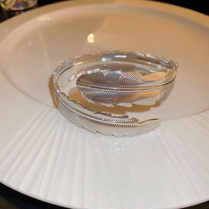 Elegante bracciale rigido aperto argento a forma di piuma con trame fini e lucentezza