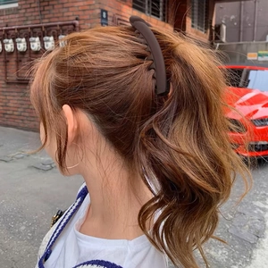 Matte dark brown banana hair clip securing a ponytail on a brunette model's curly hair