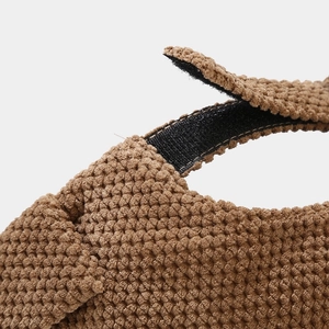 Close-up of brown knit skull cap with adjustable black hook and loop strap detail