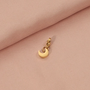 Minimalist golden stainless steel crescent moon pendant on textured pink fabric backdrop