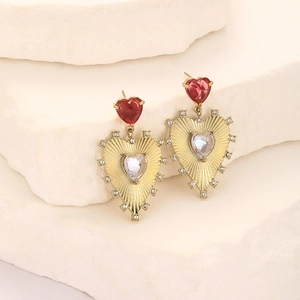 Macro view of gold plated heart earrings with zircon inlay on natural stone background