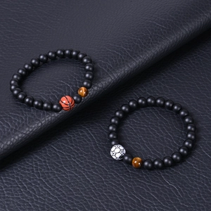 Detail of basketball and soccer beaded bracelets with tiger eye stones on leather background