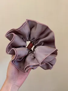 Macro detail of large satin scrunchie in dusty pink with elegant pleated fabric texture