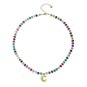 Close-up of bohemian colorful gemstone beaded necklace with golden bubble letter C pendant