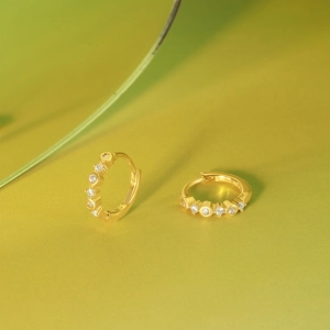 Detail of S925 sterling silver stamp on golden hoop earrings with clear cubic zirconia