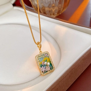 Detailed close-up of golden vintage pendant with enamel flower bird design and pearl