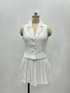 Détail d'un ensemble deux pièces blanc avec gilet sans manches et jupe plissée courte