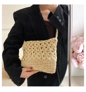 Close-up of beige woven straw crossbody bag with hollow floral pattern and shoulder strap