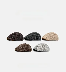Flat lay of tweed newsboy hats in five plaid patterns including black, red and beige
