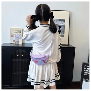 Detail of a purple sequined kids crossbody bag with rainbow strap worn by a child