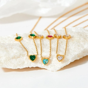 Elegant gold heart necklaces with colorful zircon stones on white mineral stones