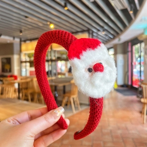 Gros plan sur un serre-tête de Noël tricoté rouge avec décoration Père Noël en peluche