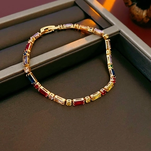 Close-up of a gold-plated bracelet with multicolored rectangular zircons in a gift box